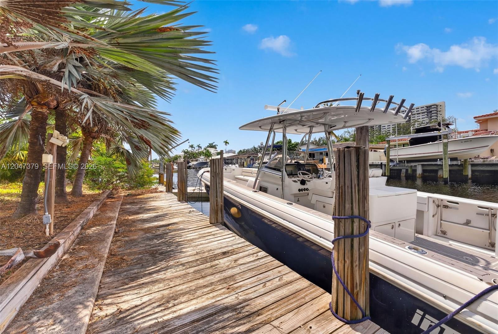 A white center console boat is docked at a wooden pier beside palm trees — 2472 SE 13th Ct, Pompano Beach FL 33062, POMPANO BEACH, FL