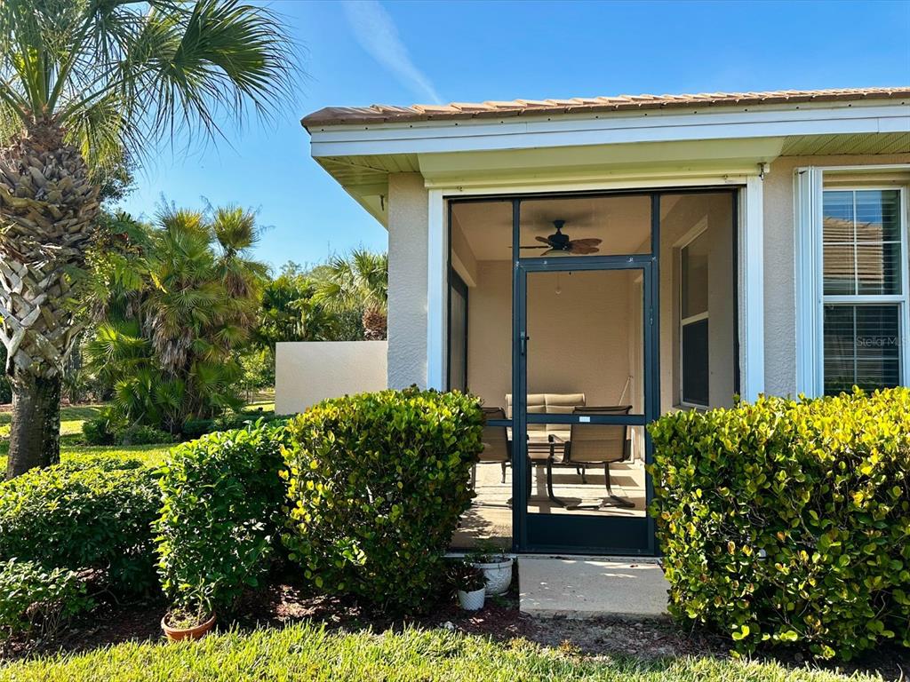A screened-in patio with outdoor furniture sits beside a house with a palm tree — 10726 CETRELLA DRIVE, FORT MYERS, FL