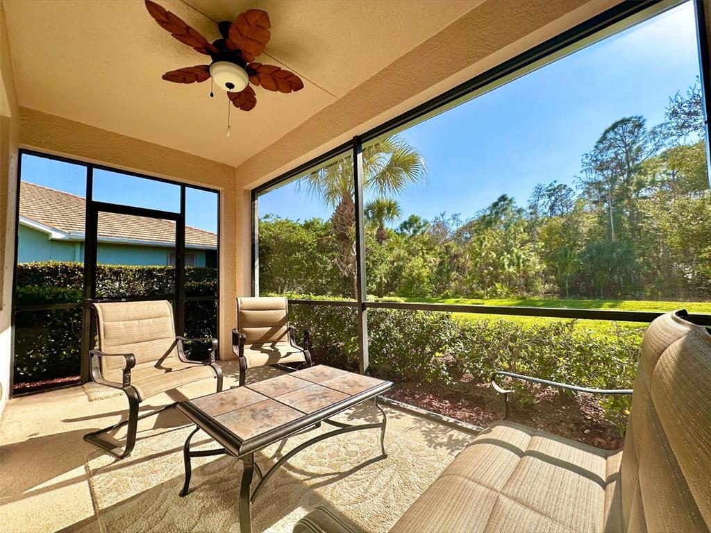 A screened-in patio features a ceiling fan, outdoor furniture, and a view of lush landscaping — 10726 CETRELLA DRIVE, FORT MYERS, FL
