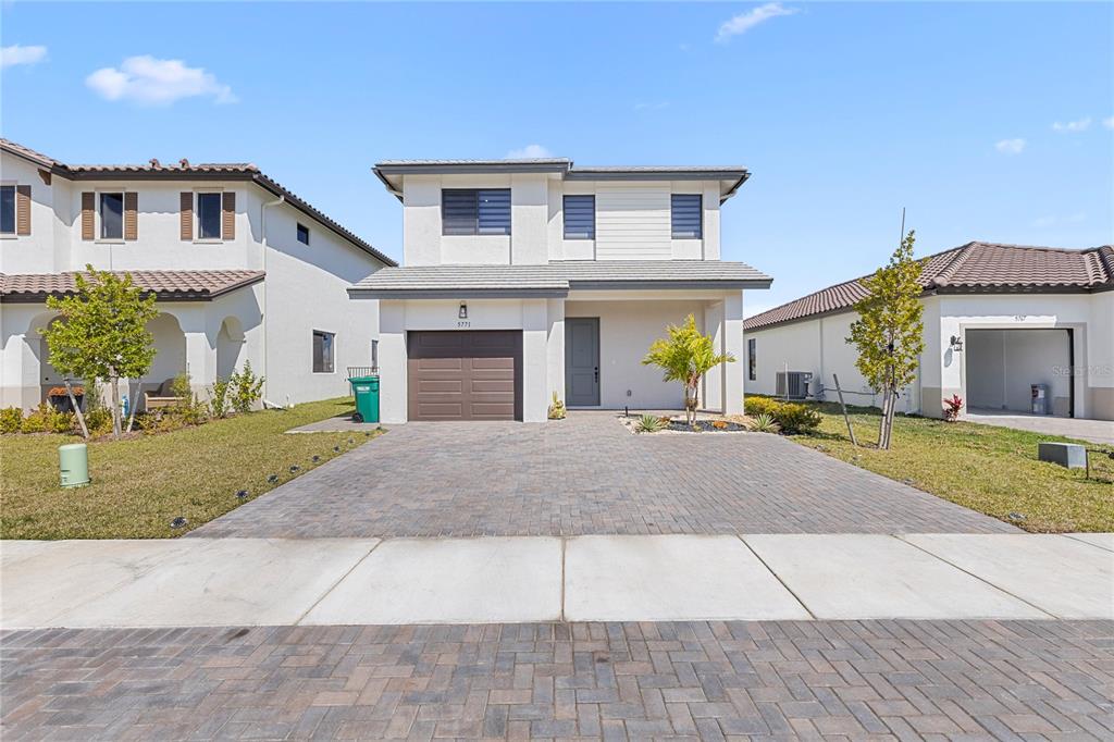 A two-story house with a brown garage door, paved driveway, and light-colored exterior walls — 5771 AGOSTINO WAY, AVE MARIA, FL