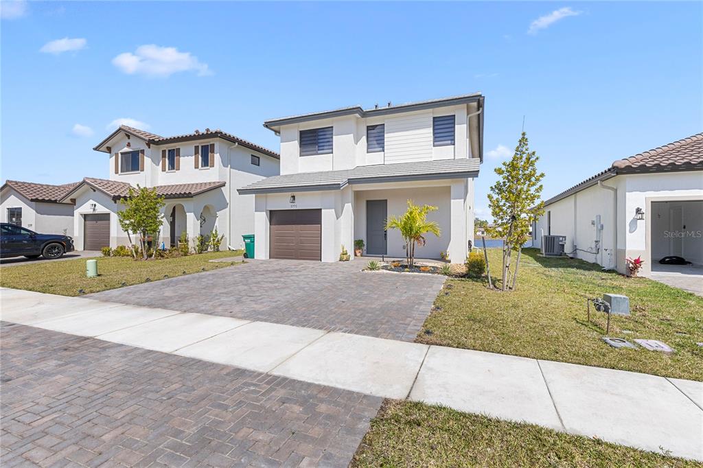A two-story suburban house with a paved driveway, a garage, and a small front yard — 5771 AGOSTINO WAY, AVE MARIA, FL