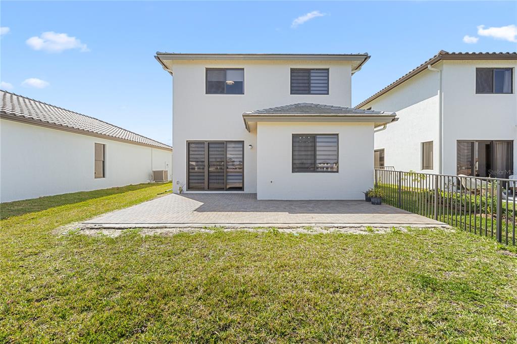 The back exterior of a two-story house with a paved patio and a fenced yard — 5771 AGOSTINO WAY, AVE MARIA, FL
