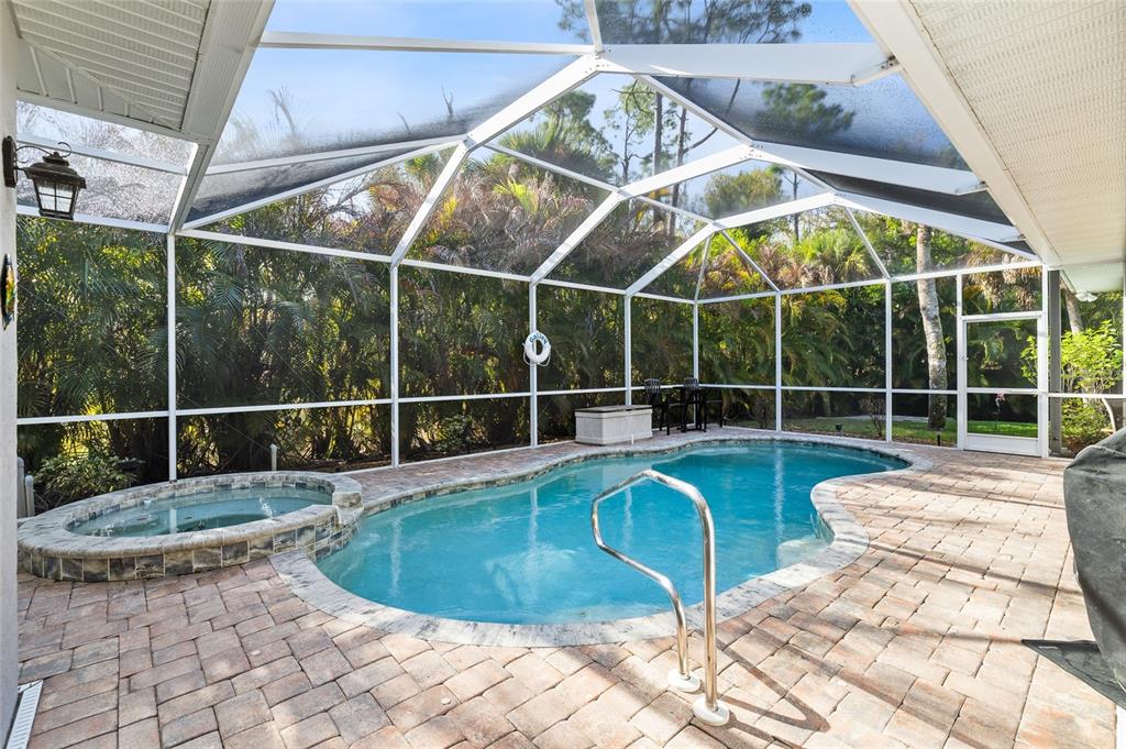 A screened-in patio features a swimming pool, a raised hot tub, and paver decking — 3730 CRANDON ROAD, NORTH PORT, FL