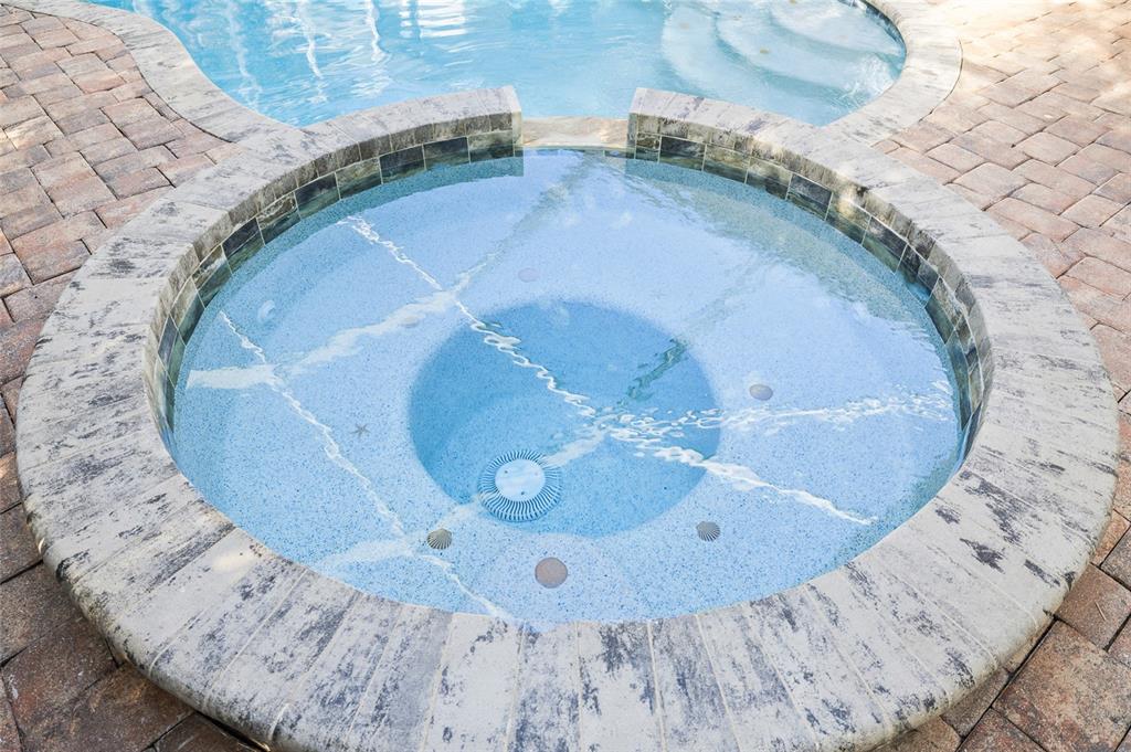 A circular hot tub with decorative shell accents sits next to a swimming pool — 3730 CRANDON ROAD, NORTH PORT, FL
