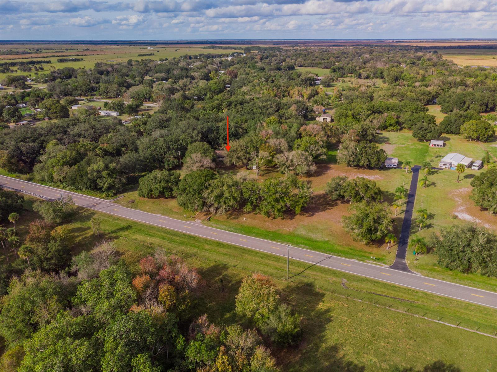 An aerial view shows a rural property with a house partially obscured by trees — 3453 NW 160th Street, Okeechobee FL 34972, OKEECHOBEE, FL