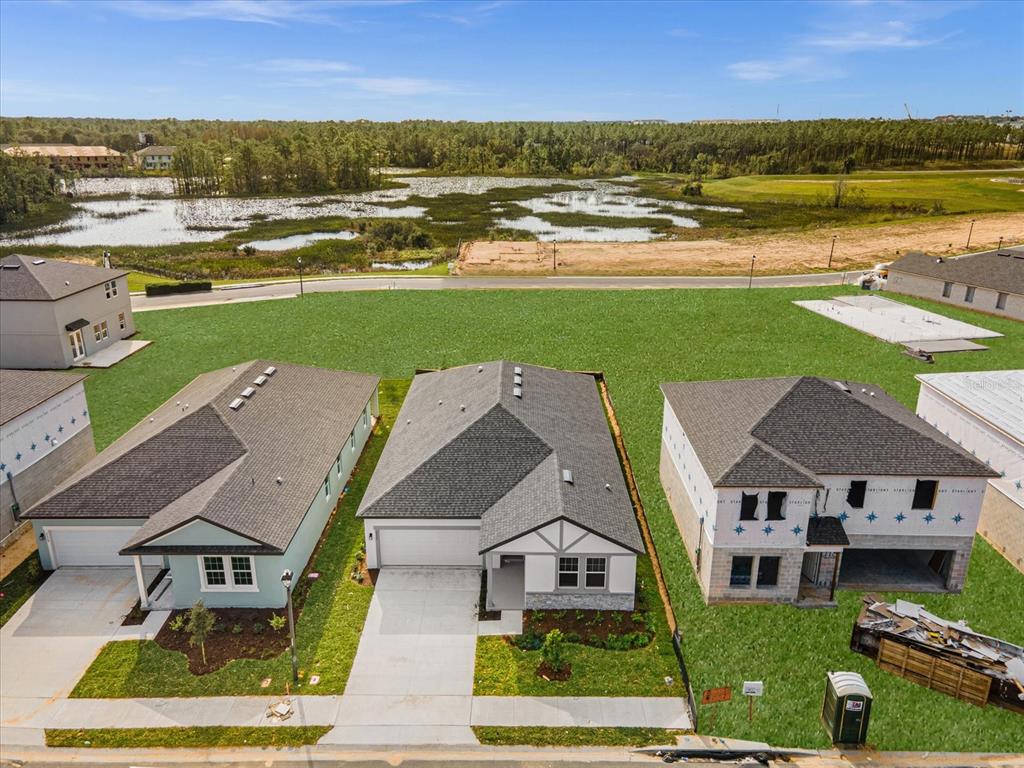 An aerial view shows three suburban houses, including two under construction, near a large pond — 2355 LANCASHIRE STREET, DAVENPORT, FL
