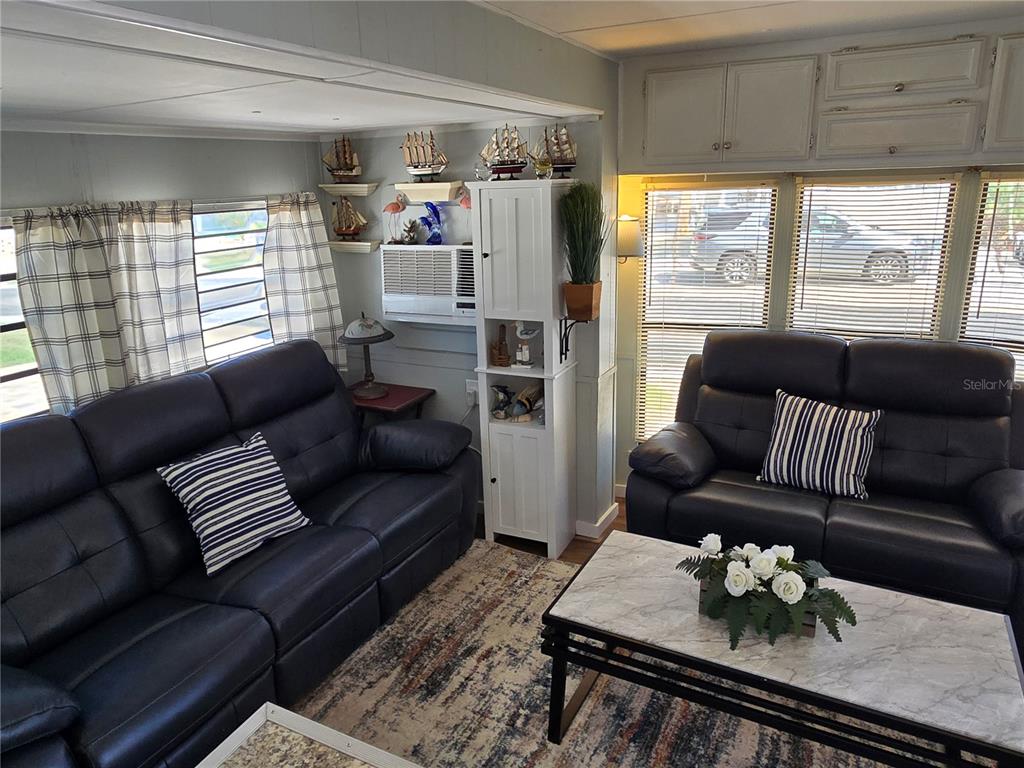 A living room features two dark leather sofas, a marble-topped coffee table, and nautical decor — 2043 KETCH CIRCLE UNIT C7, PALM HARBOR, FL