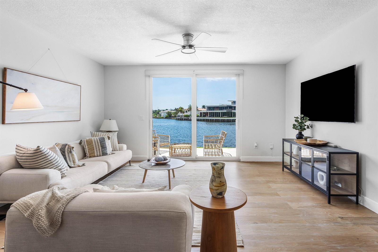 A living room with a sofa, television, and sliding doors overlooking a waterfront view — 900 E Jeffery Street, Boca Raton FL 33487, BOCA RATON, FL