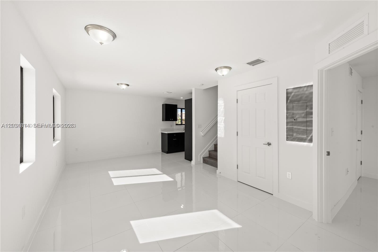 A bright, minimalist room features white tile floors, white walls, and a small kitchen area — 2243 NW 50th St # 2, Miami FL 33142, MIAMI, FL