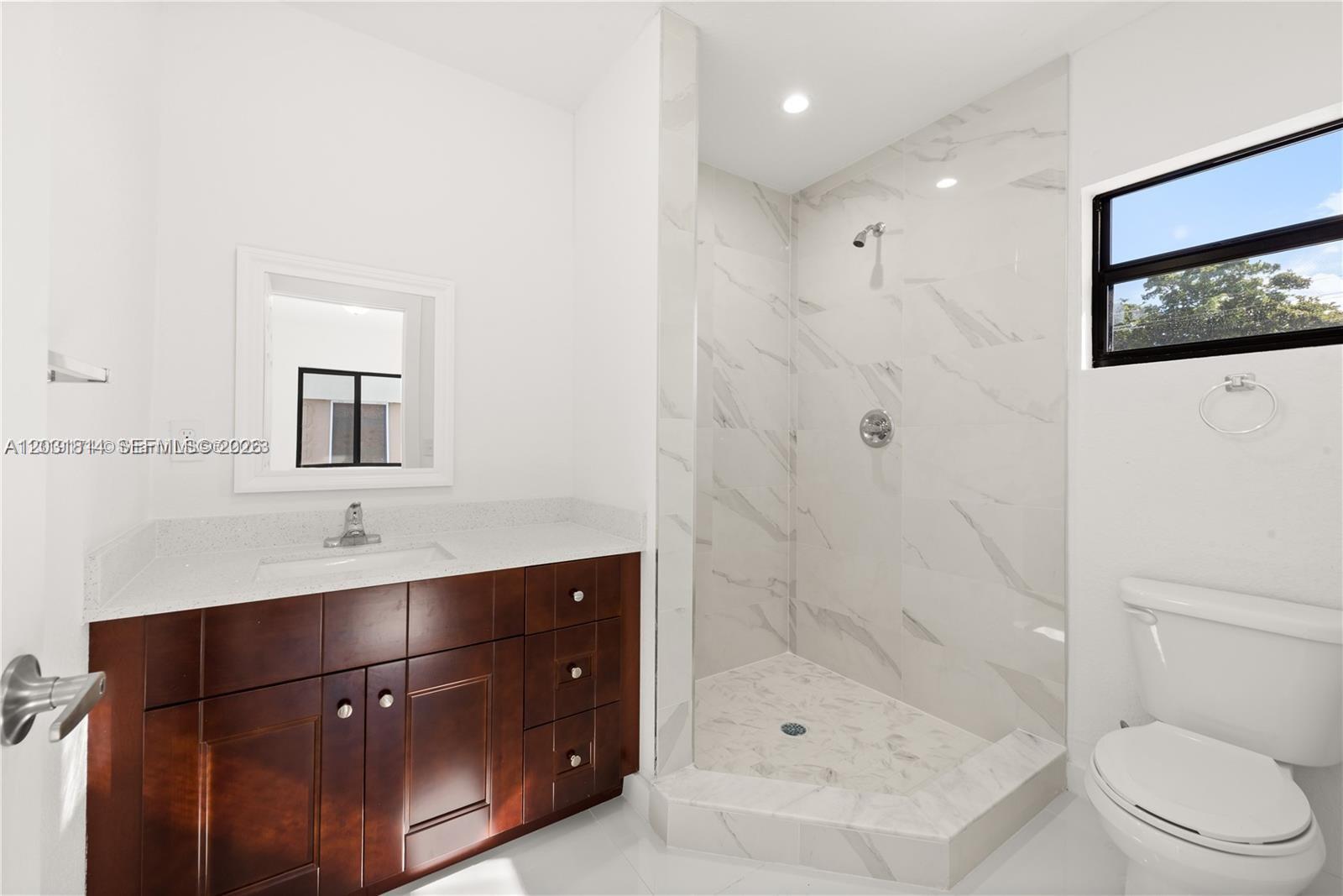 A bathroom features a dark wood vanity, a walk-in shower, and a white toilet — 2243 NW 50th St # 2, Miami FL 33142, MIAMI, FL