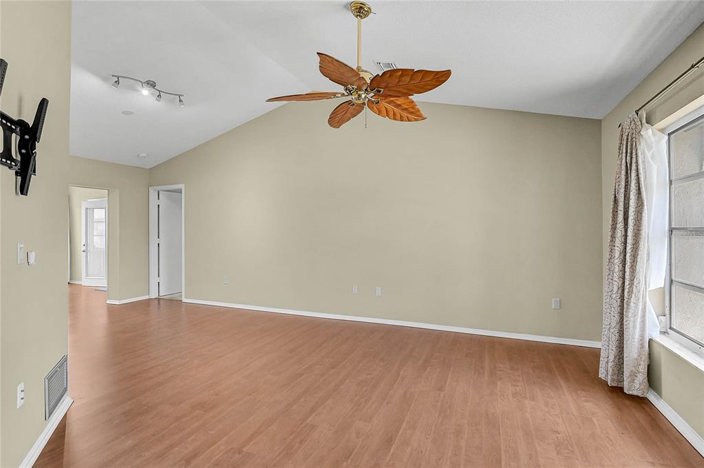 A living room features light-colored walls, wood-look flooring, a vaulted ceiling, and a ceiling fan — 5852 LINCOLN ROAD, VENICE, FL