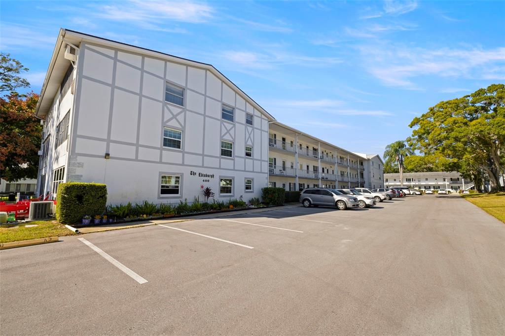 A multi-story white apartment building with an open-air walkway and a parking lot — 400 GLENNES LANE UNIT 206, DUNEDIN, FL