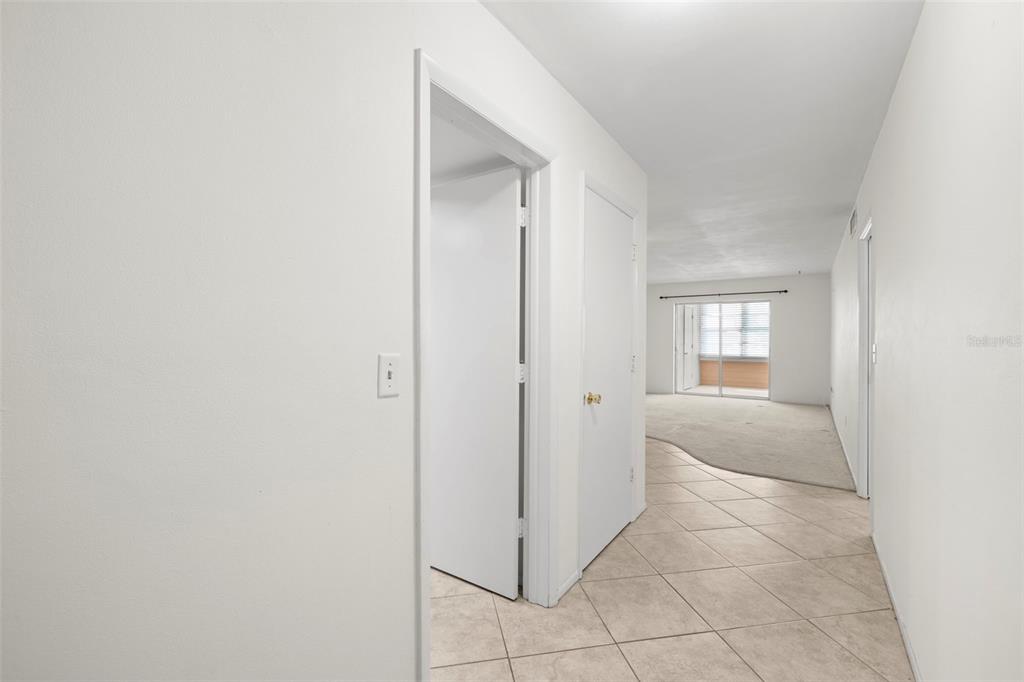 An outdoor walkway with a white railing overlooks a parking lot with several cars — 400 GLENNES LANE UNIT 206, DUNEDIN, FL