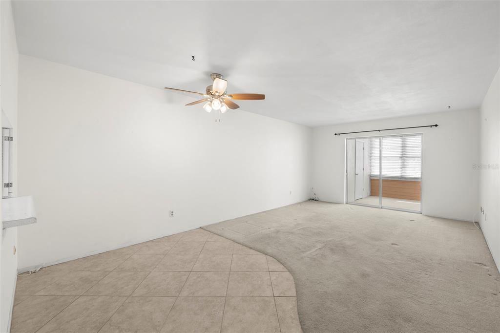 A hallway with tile flooring leads to a carpeted living area with a sliding glass door — 400 GLENNES LANE UNIT 206, DUNEDIN, FL