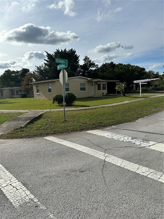 A street corner view shows a single-story house with a lawn and street signs — 2302 IDAHO ROAD, DELTONA, FL