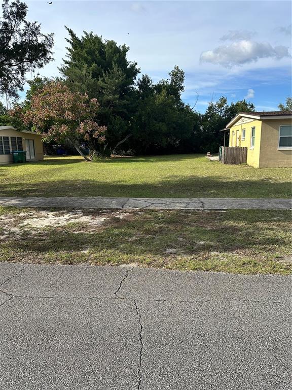 A vacant grassy lot sits between two single-story houses under a blue sky — 2302 IDAHO ROAD, DELTONA, FL