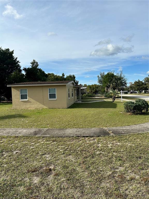 A tan, single-story house sits on a grassy lot with a sidewalk in the foreground — 2302 IDAHO ROAD, DELTONA, FL
