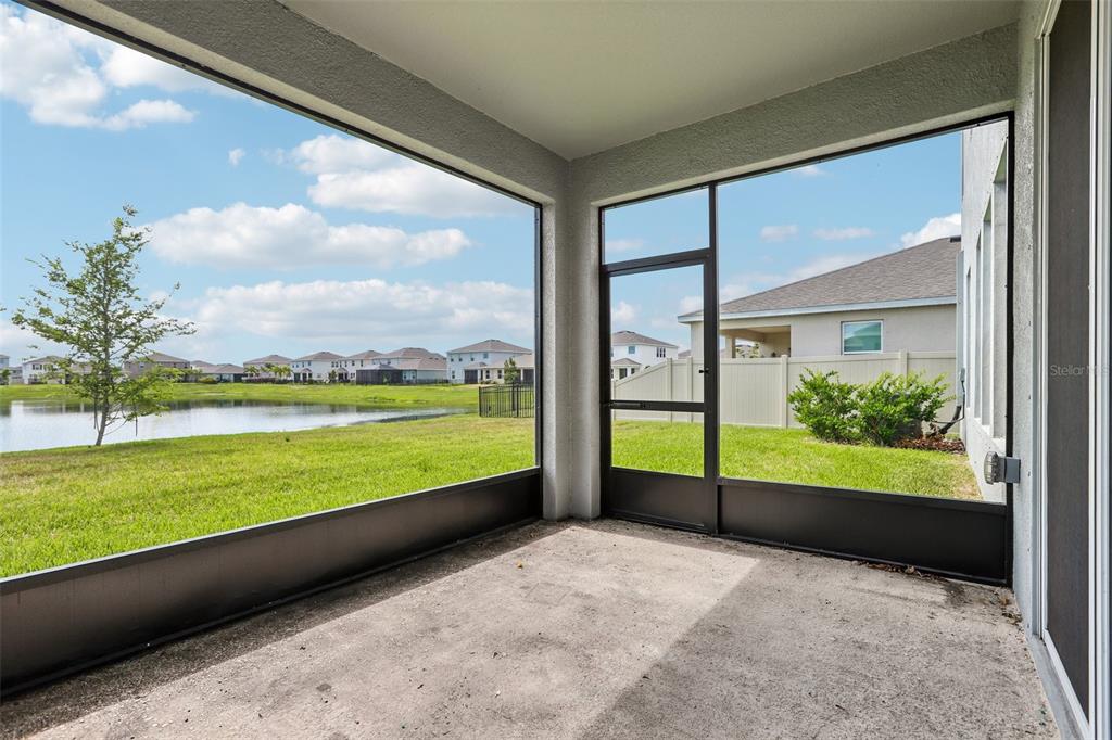 A screened-in concrete patio overlooks a grassy lawn and a pond under a blue sky — 327 MANGROVE MANOR DRIVE, APOLLO BEACH, FL