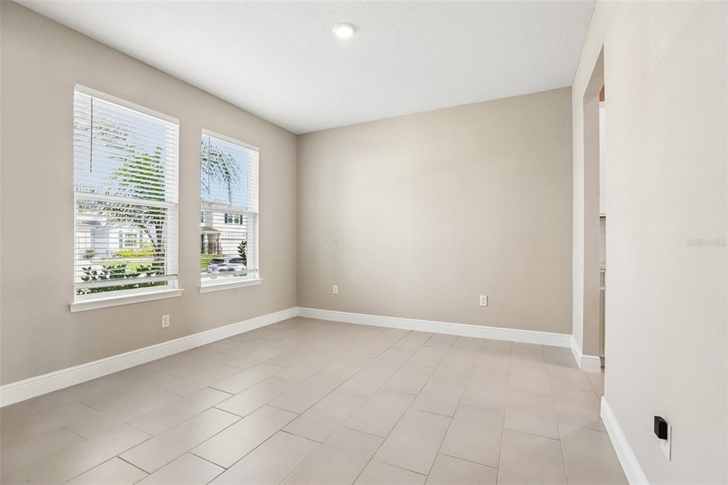 An empty room with light-colored tile flooring, beige walls, and two windows with blinds — 327 MANGROVE MANOR DRIVE, APOLLO BEACH, FL
