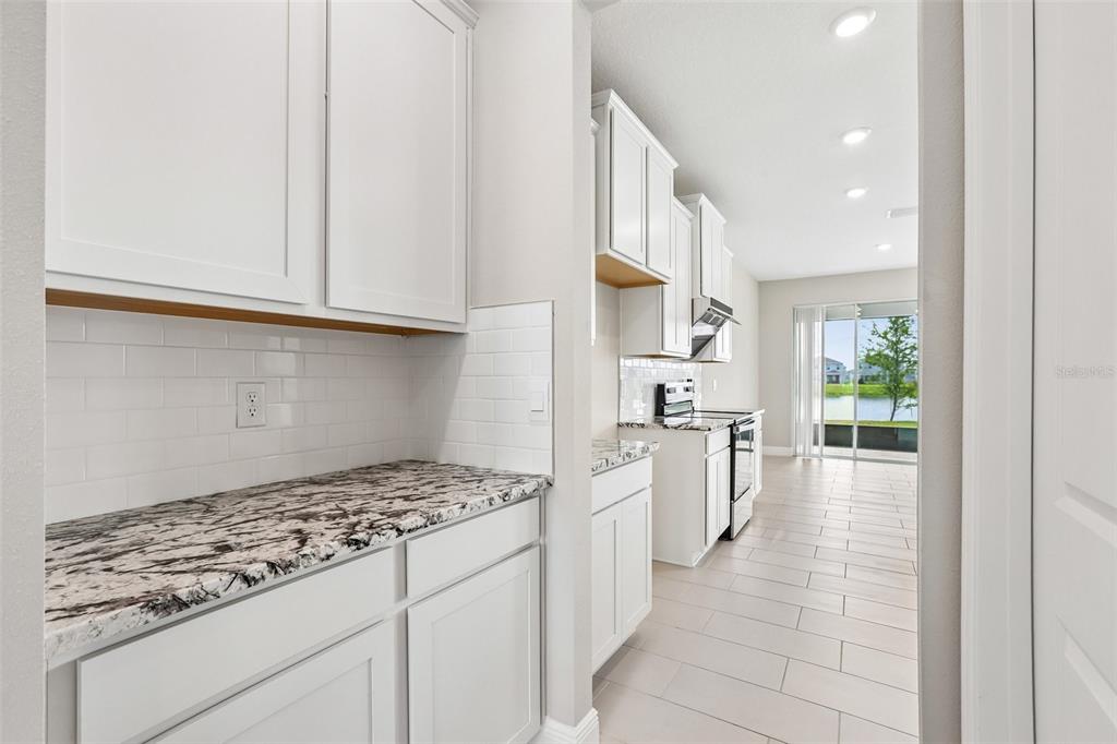 A kitchen with white cabinets, granite countertops, subway tile backsplash, and tile flooring — 327 MANGROVE MANOR DRIVE, APOLLO BEACH, FL