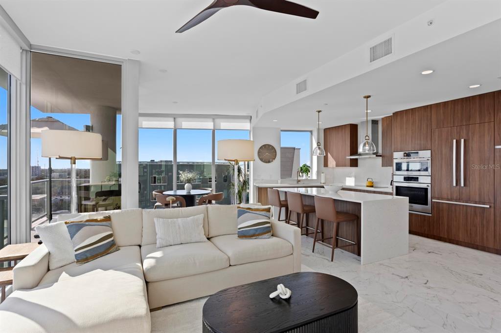 A modern open-concept living room and kitchen with marble floors, wood cabinetry, and floor-to-ceiling windows — 777 3RD AVENUE N UNIT 1208, ST PETERSBURG, FL