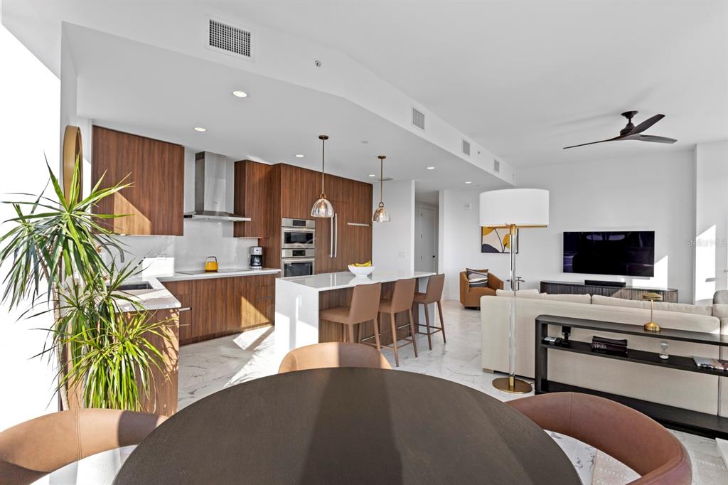 An open-concept kitchen and living area featuring wood cabinetry, a marble island, and tile flooring — 777 3RD AVENUE N UNIT 1208, ST PETERSBURG, FL