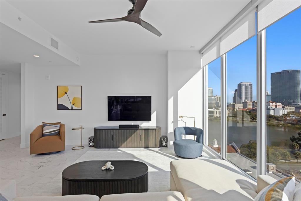 A modern living room features a television, floor-to-ceiling windows with city views, and marble flooring — 777 3RD AVENUE N UNIT 1208, ST PETERSBURG, FL
