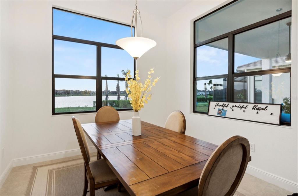 A dining area features a wooden table, four chairs, a pendant light, and large windows — 9132 BERNINI PLACE, SARASOTA, FL
