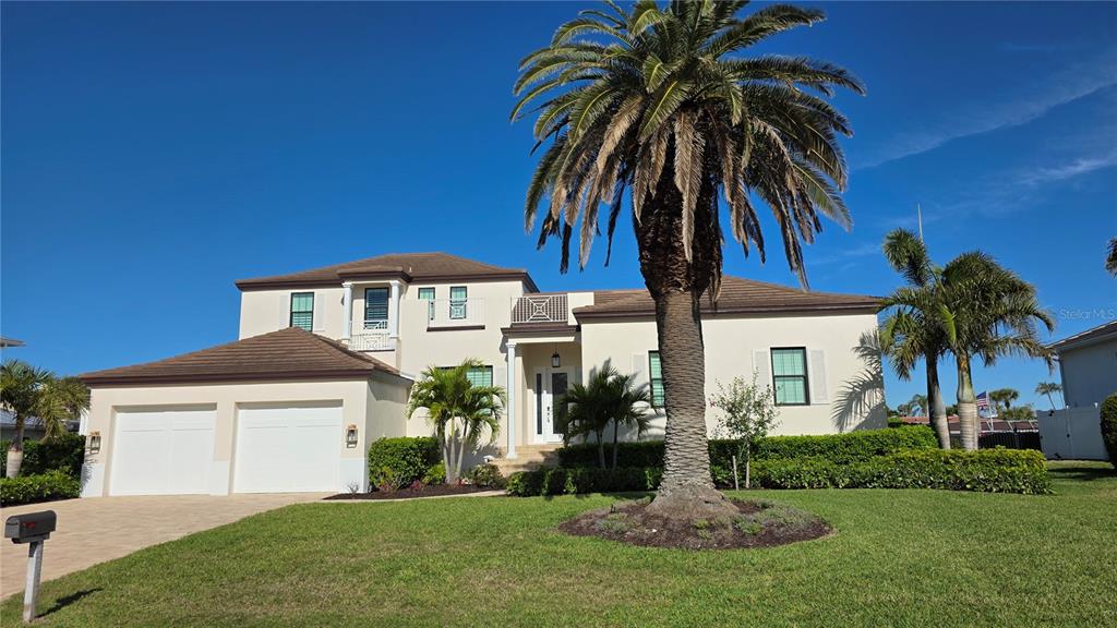 A two-story stucco house with a two-car garage and a large palm tree in front — 531 BIRDIE LANE, LONGBOAT KEY, FL