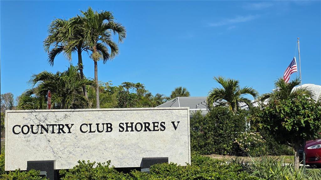 A stone sign reads Country Club Shores V in front of palm trees and a flag — 531 BIRDIE LANE, LONGBOAT KEY, FL