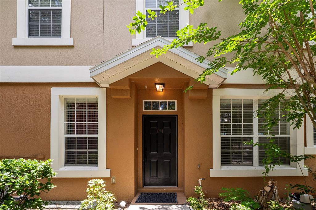 The exterior of a tan house features a black front door under a small gable roof — 494 ASHLEY BROOKE COURT UNIT A, APOPKA, FL