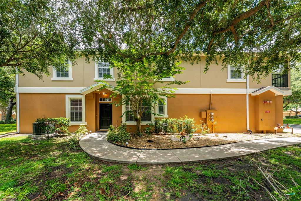 A two-story tan apartment building features a front entrance, a sidewalk, and mature trees — 494 ASHLEY BROOKE COURT UNIT A, APOPKA, FL