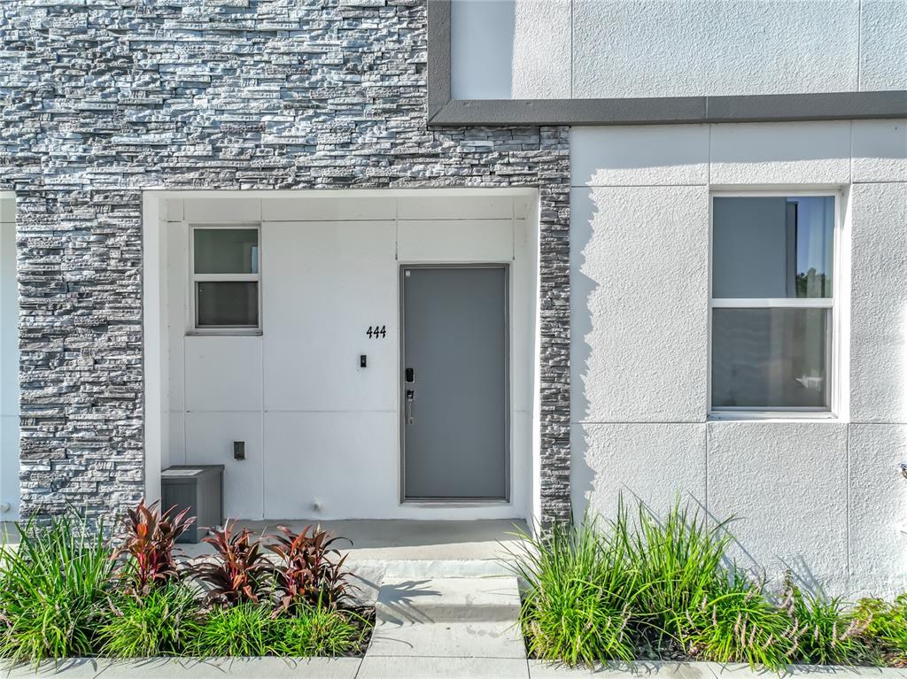The exterior of a modern townhouse features a stone facade, a gray door, and landscaping — 444 FAMAGUSTA DRIVE, DAVENPORT, FL