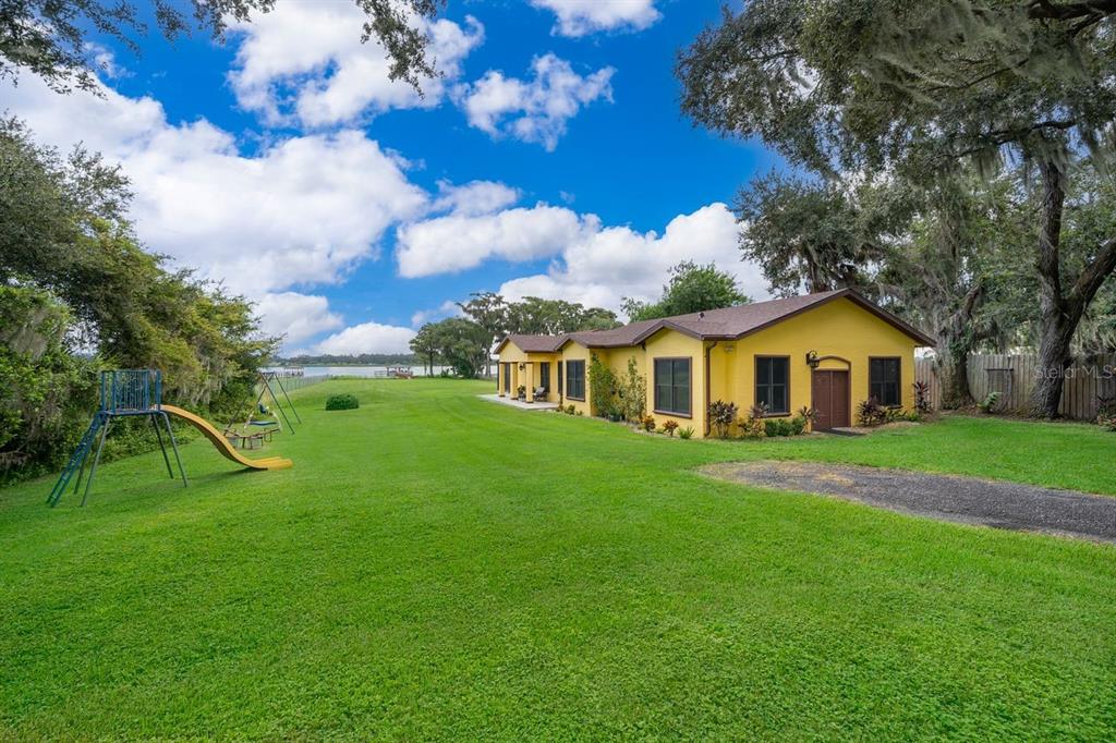 A yellow house with a large grassy backyard, a playground, and a view of water — 2339 NEPTUNE ROAD Unit A, KISSIMMEE, FL