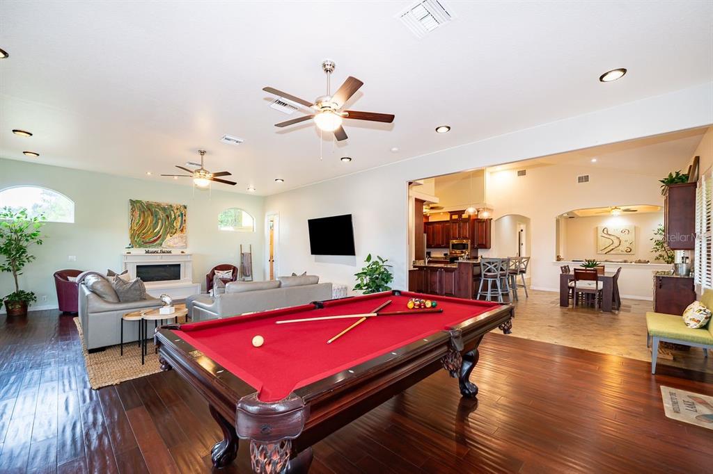 A spacious open-concept living area features a pool table, hardwood floors, and a kitchen beyond — 2339 NEPTUNE ROAD Unit A, KISSIMMEE, FL