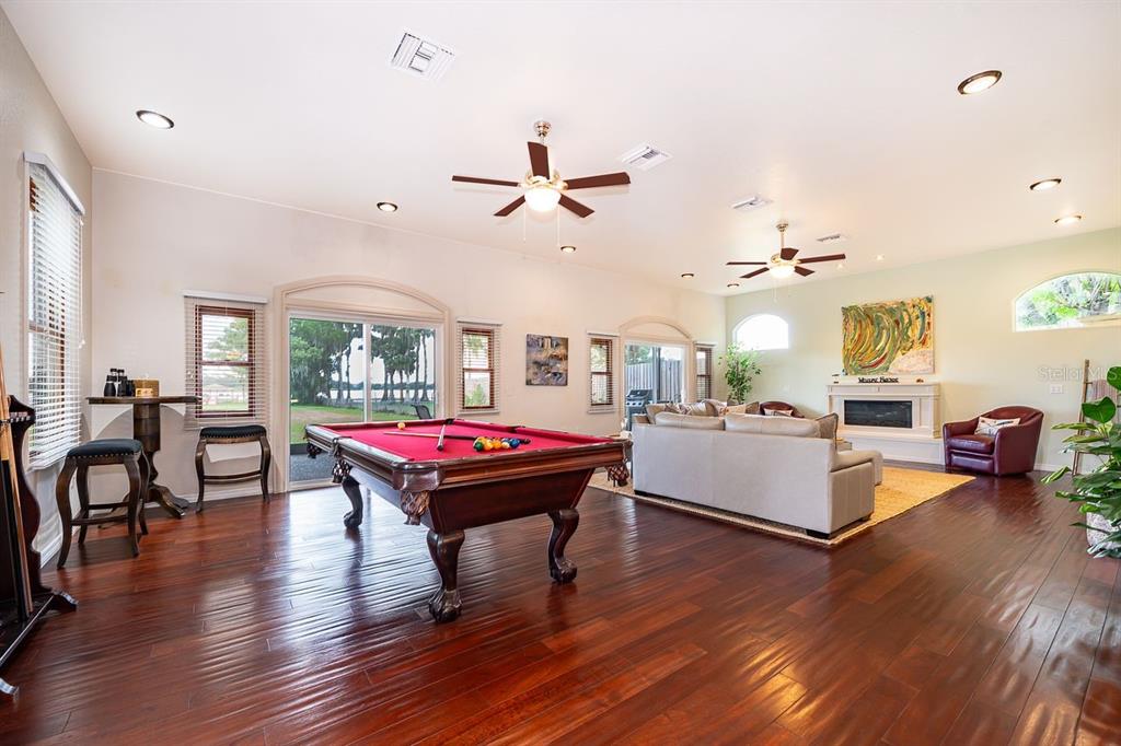 A spacious living room features a pool table, hardwood floors, and a fireplace — 2339 NEPTUNE ROAD Unit A, KISSIMMEE, FL
