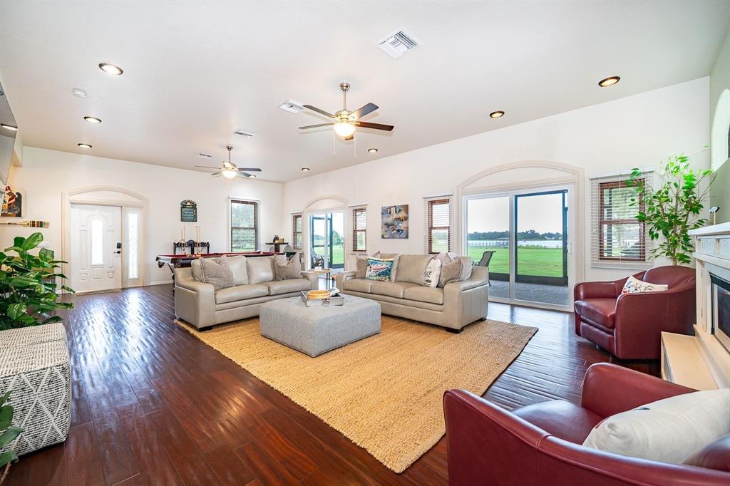 A spacious living room features hardwood floors, two sofas, red armchairs, and a sliding glass door — 2339 NEPTUNE ROAD Unit A, KISSIMMEE, FL