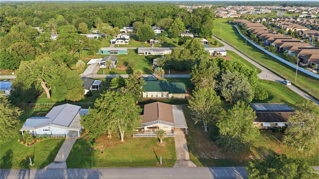 An aerial view shows several single-story residential houses with driveways surrounded by trees and lawns — 10040 SW 98TH AVENUE, OCALA, FL