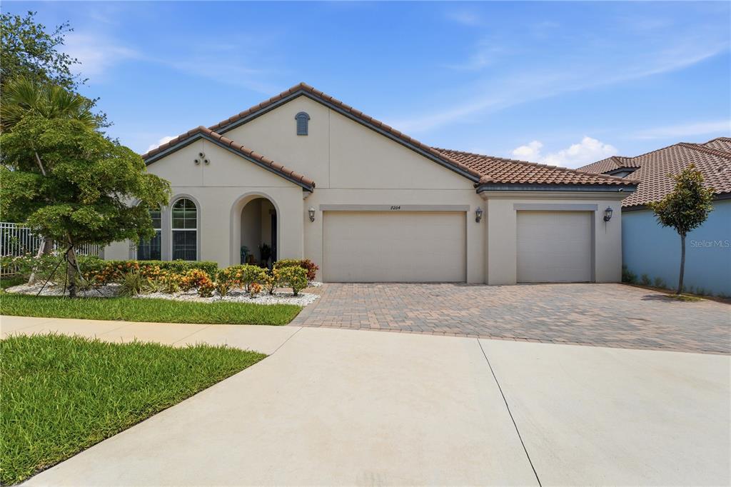 A single-story house with a beige stucco exterior, tile roof, and a three-car garage — 7204 GREAT EGRET BOULEVARD, SARASOTA, FL