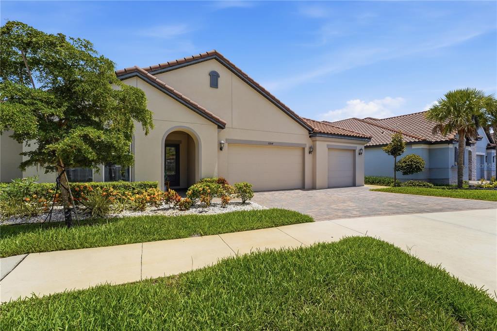 A single-story house with a beige stucco exterior, a three-car garage, and a paved driveway — 7204 GREAT EGRET BOULEVARD, SARASOTA, FL