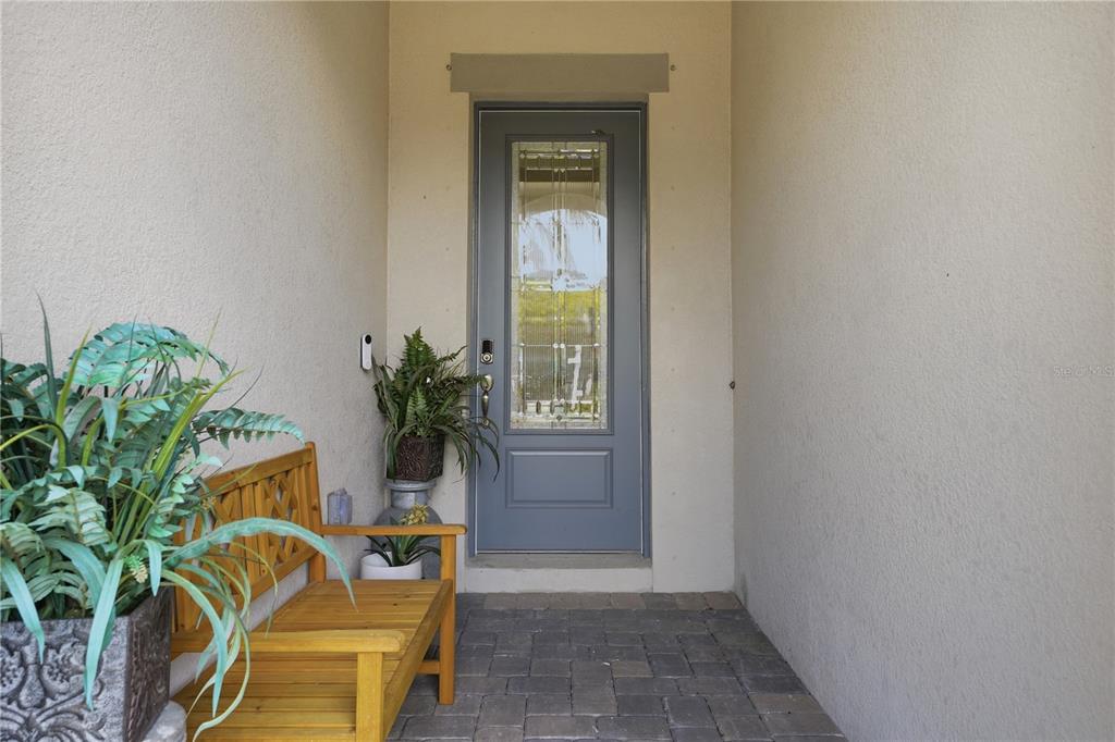 A gray front door with a glass insert sits at the end of a covered entryway — 7204 GREAT EGRET BOULEVARD, SARASOTA, FL