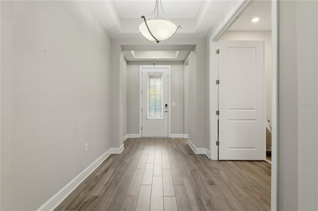 A bright entryway features light gray walls, wood-look tile flooring, and a decorative glass door — 7204 GREAT EGRET BOULEVARD, SARASOTA, FL