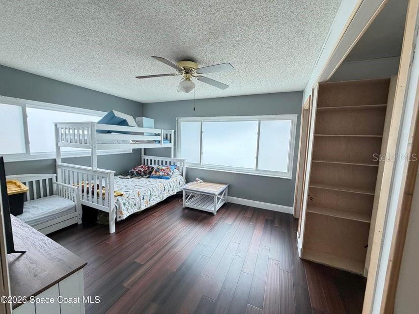 A bedroom features dark wood flooring, a white bunk bed, and built-in wall shelving — 1578 W POWDER HORN ROAD, TITUSVILLE, FL