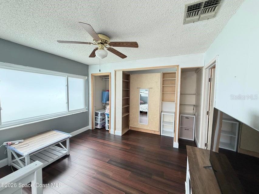 A bedroom features dark wood flooring, a ceiling fan, and a built-in wall unit — 1578 W POWDER HORN ROAD, TITUSVILLE, FL
