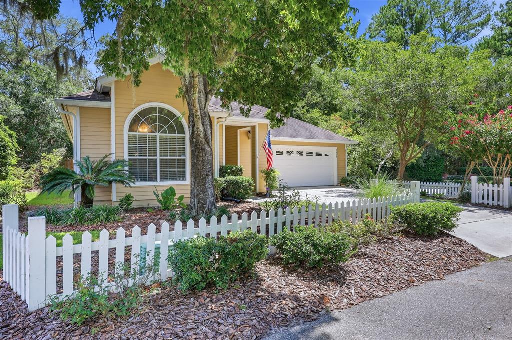 A yellow house with a white picket fence, a two-car garage, and a large tree — 9408 SW 39TH AVENUE, GAINESVILLE, FL