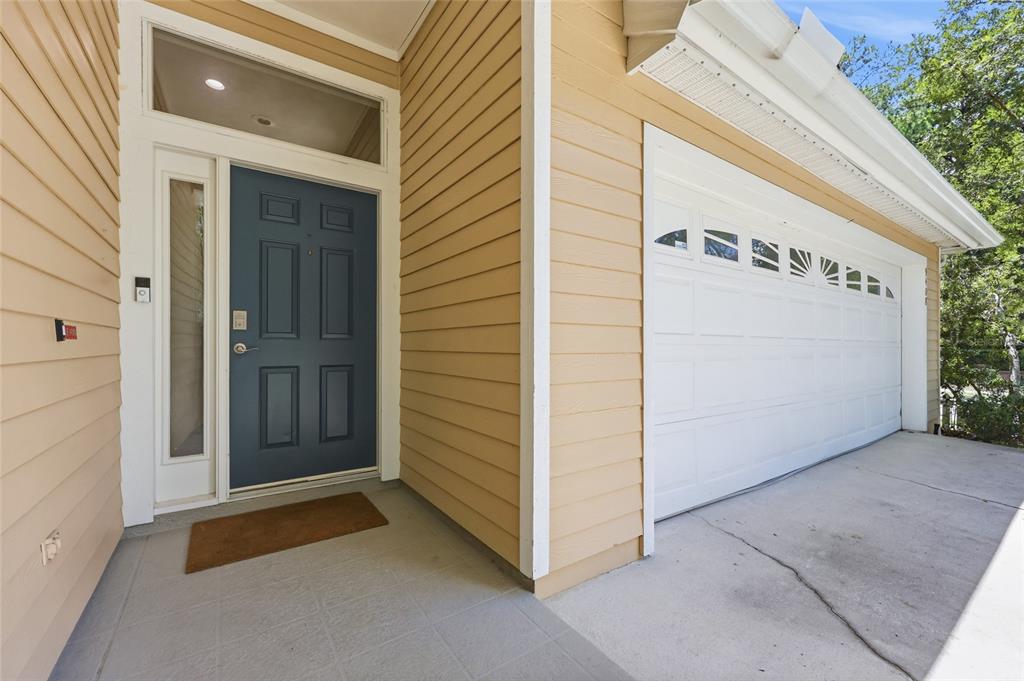 A blue front door and a white garage door are set against tan horizontal siding — 9408 SW 39TH AVENUE, GAINESVILLE, FL