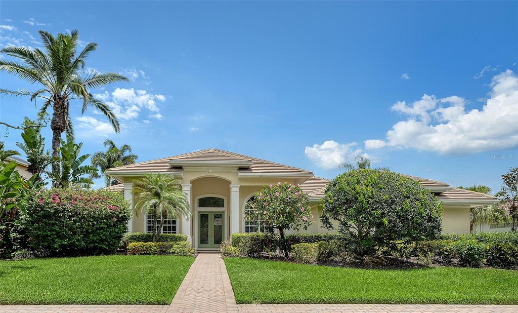 A single-story house with a tiled roof, arched entryway, and landscaped front yard — 8923 BLOOMFIELD BOULEVARD, SARASOTA, FL