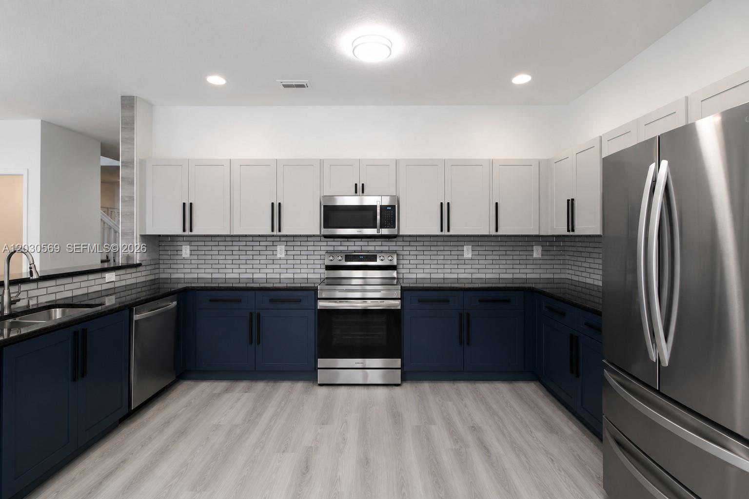 A kitchen features navy blue lower cabinets, white upper cabinets, and stainless steel appliances — 2564 SW 147th Path, Miami FL 33185, MIAMI, FL