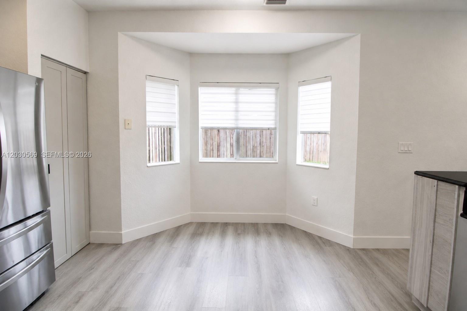 A bright dining nook features light wood-look flooring, white walls, and a three-window bay — 2564 SW 147th Path, Miami FL 33185, MIAMI, FL