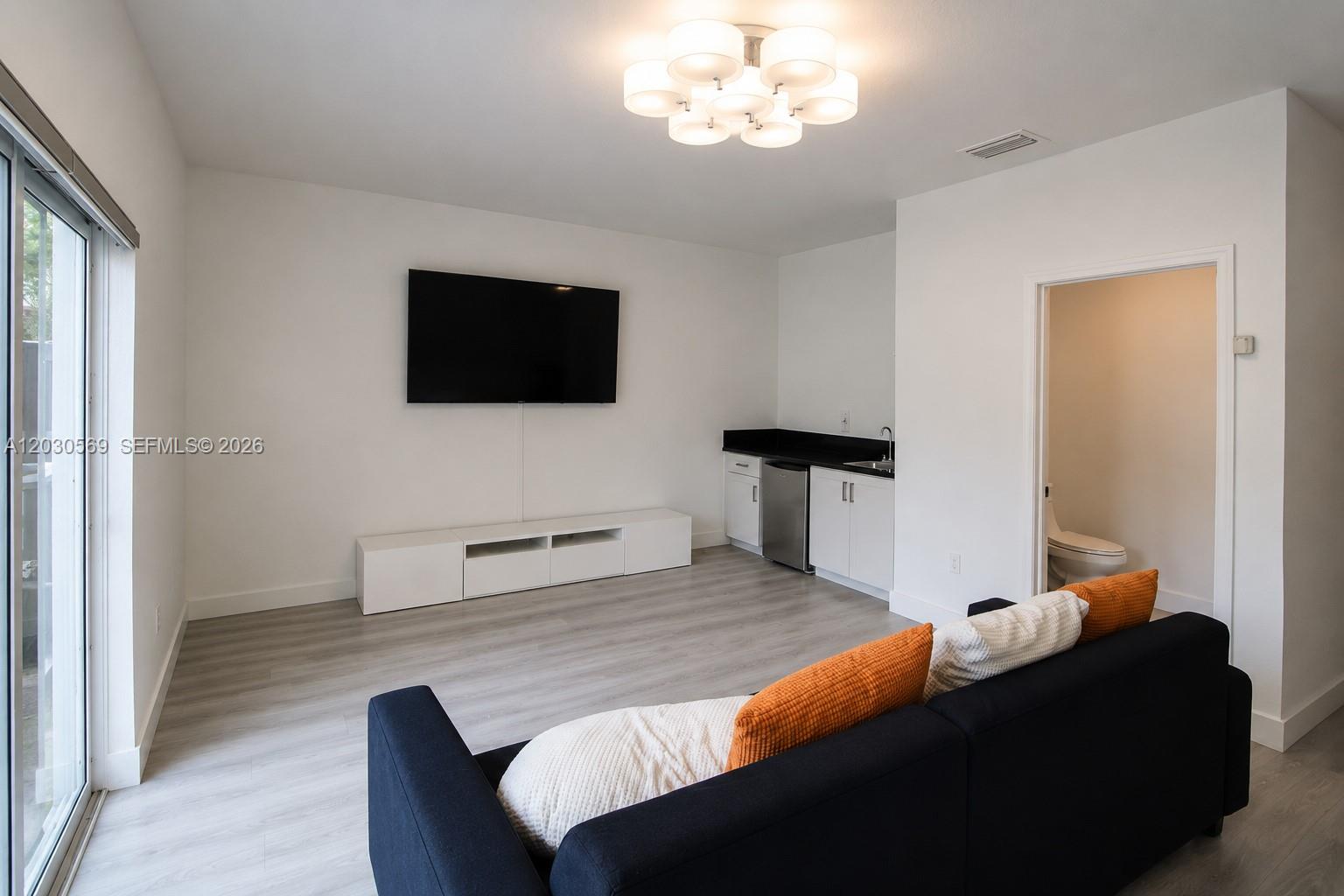 A living room features a wall-mounted television, a wet bar, and a sliding glass door — 2564 SW 147th Path, Miami FL 33185, MIAMI, FL